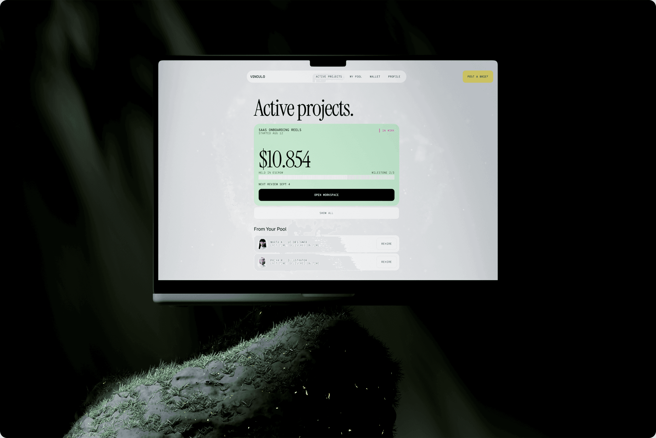 Vinculo Active projects screen on a laptop resting on a mossy stone